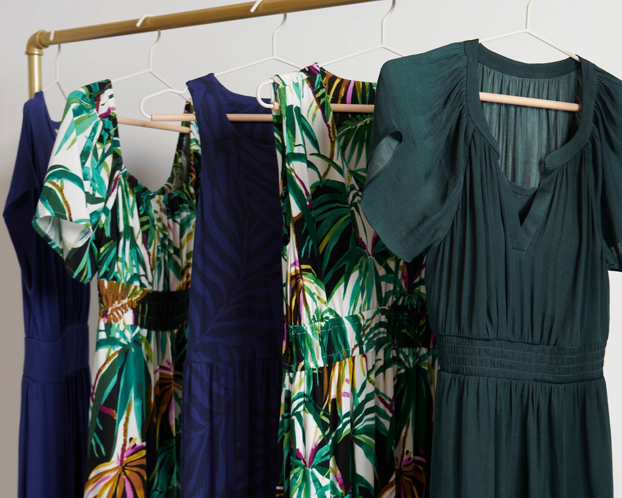 Soma<sup class=st-superscript>®</sup> bra dresses in solid green, blue, and palm print hanging on a clothing rack.
