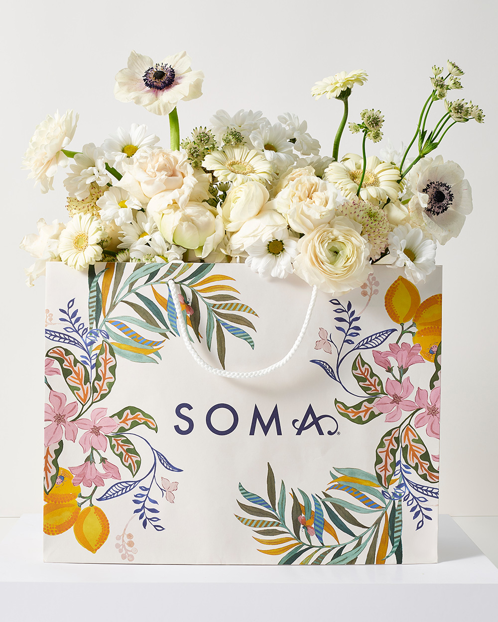 Soma<sup class=st-superscript>®</sup> shopping bag with floral design and white floral blooms inside of bag.