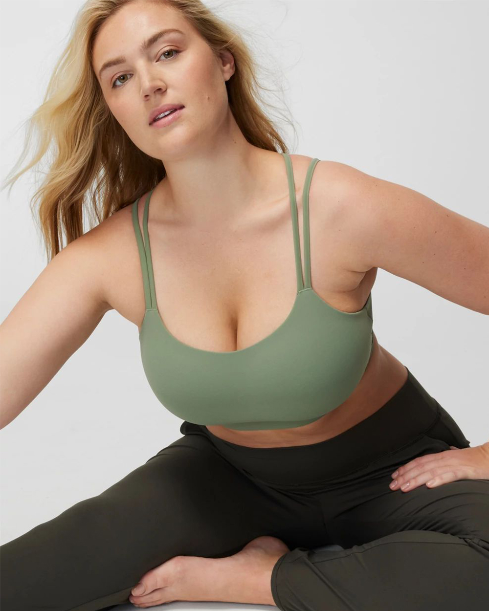 Soma<sup class=st-superscript>®</sup> model wearing a light green sports bra, and dark olive leggings.