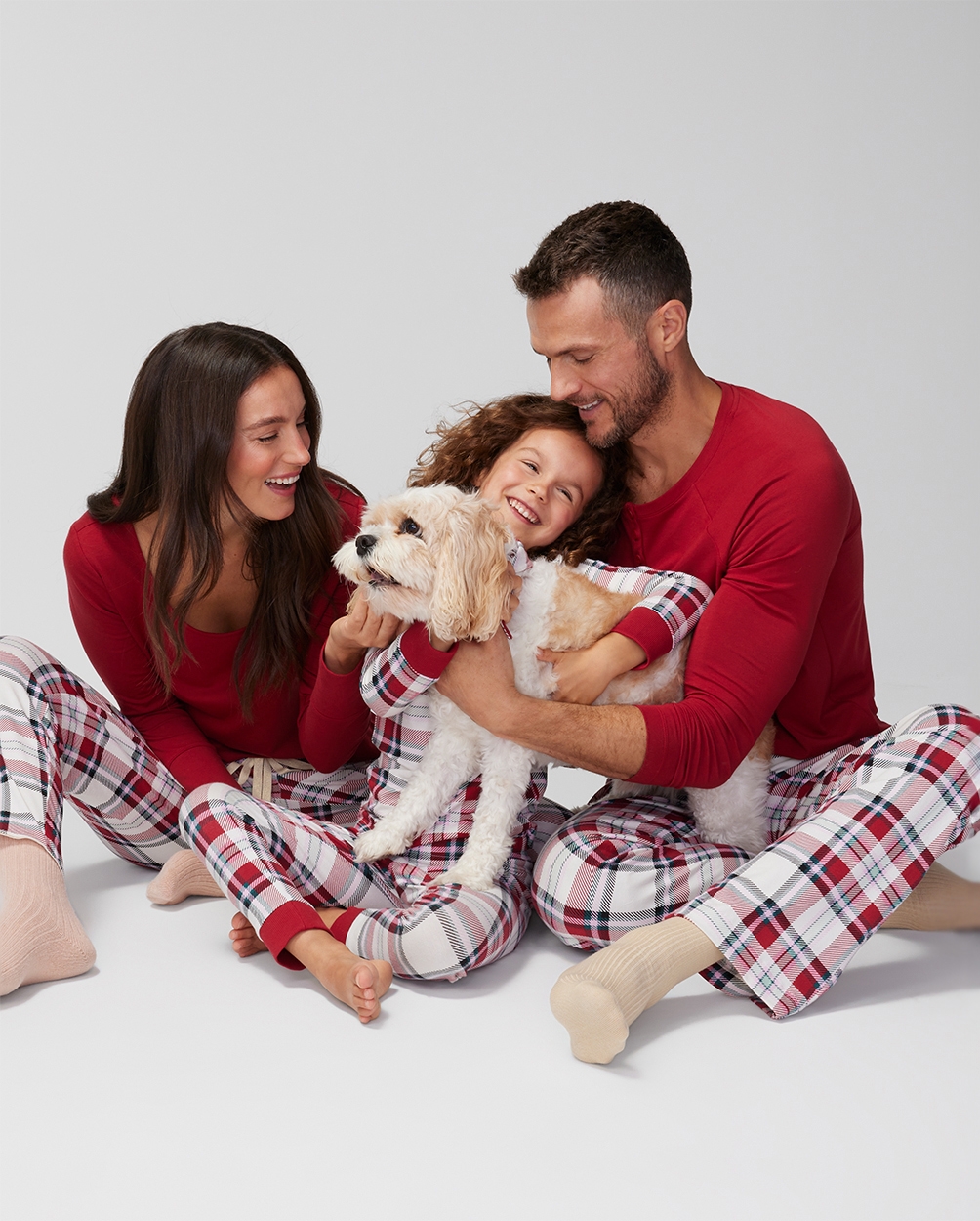 Soma<sup class=st-superscript>®</sup> women’s, men’s, children’s, and dog models wearing coordinating red plaid winter pajamas. 