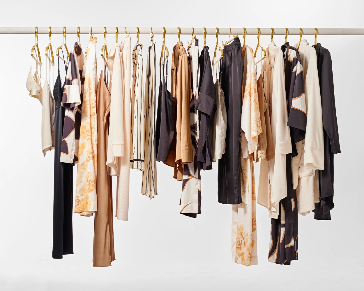 Soma<sup class=st-superscript>®</sup> off-white, black, gold, floral, and striped pajamas in a variety of styles hung up on hangers. 