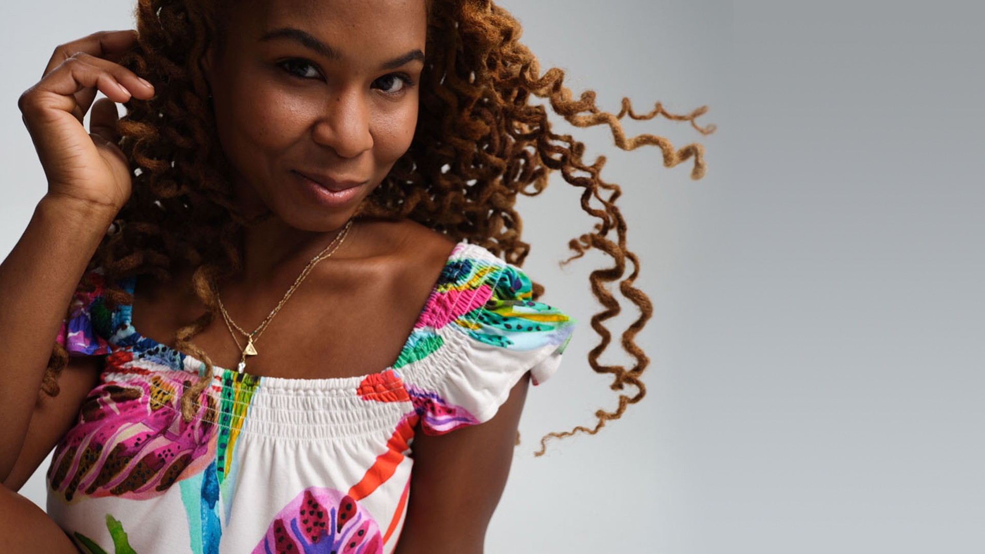 Soma women’s model wearing gold necklaces and a colorful tropical print pajama top.