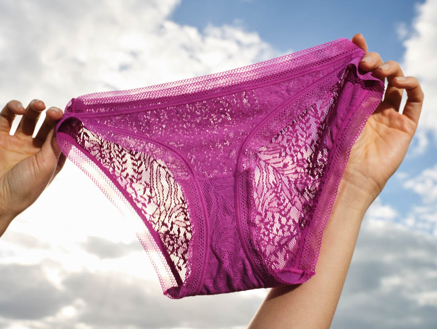 Soma<sup class=st-superscript>®</sup> women’s model’s hands holding a pair of purple all-over lace bikini panties.