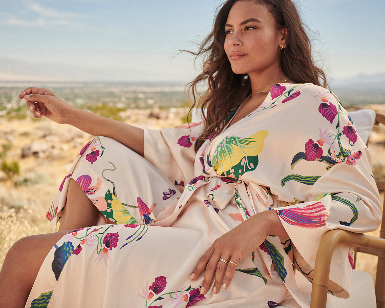 Soma<sup class=st-superscript>®</sup> model sitting in an outdoor chair, wearing a white floral print robe.