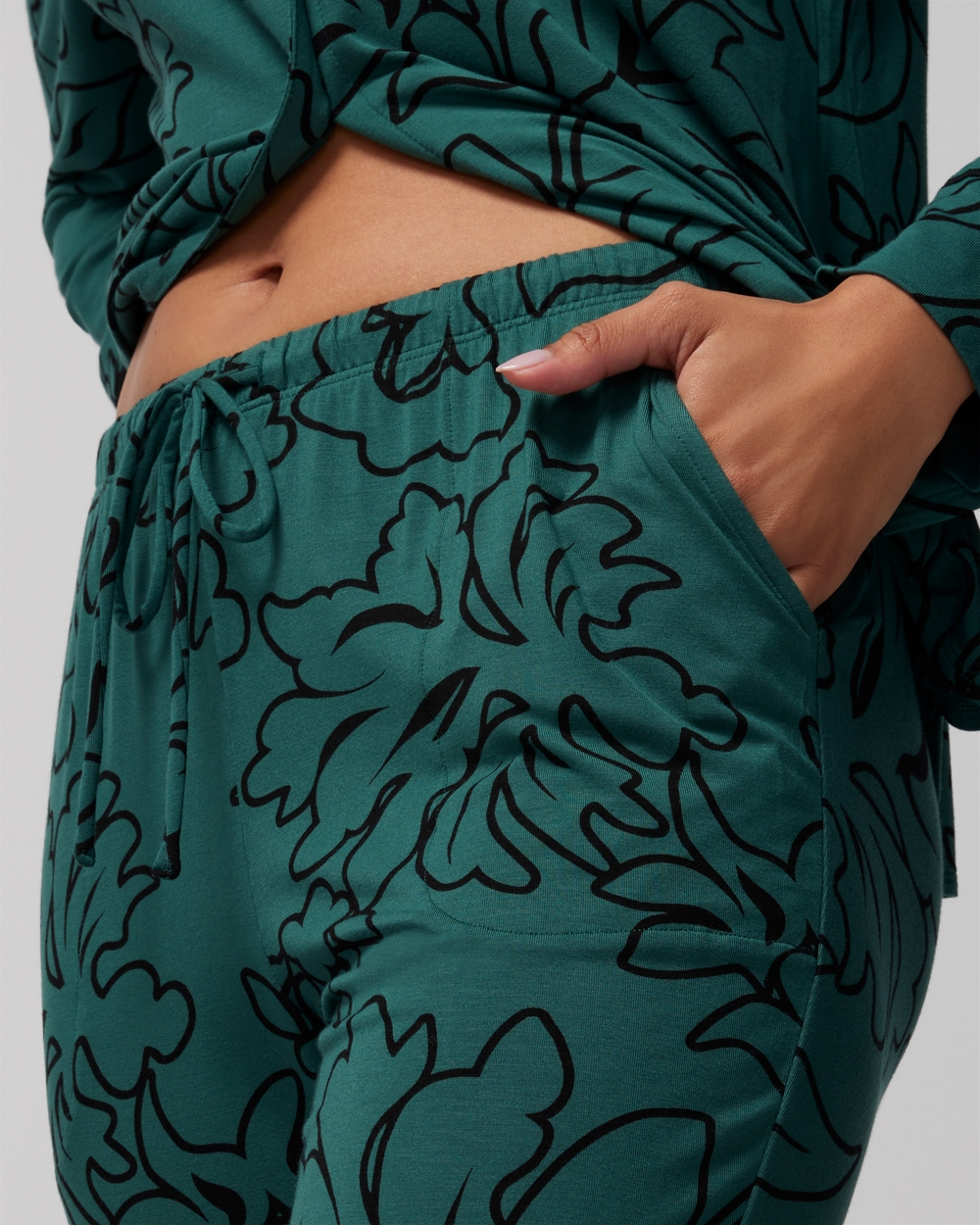 Close-up shot of Soma<sup class=st-superscript>®</sup> model wearing dark green floral pajamas and posing with her hand in a side pocket.