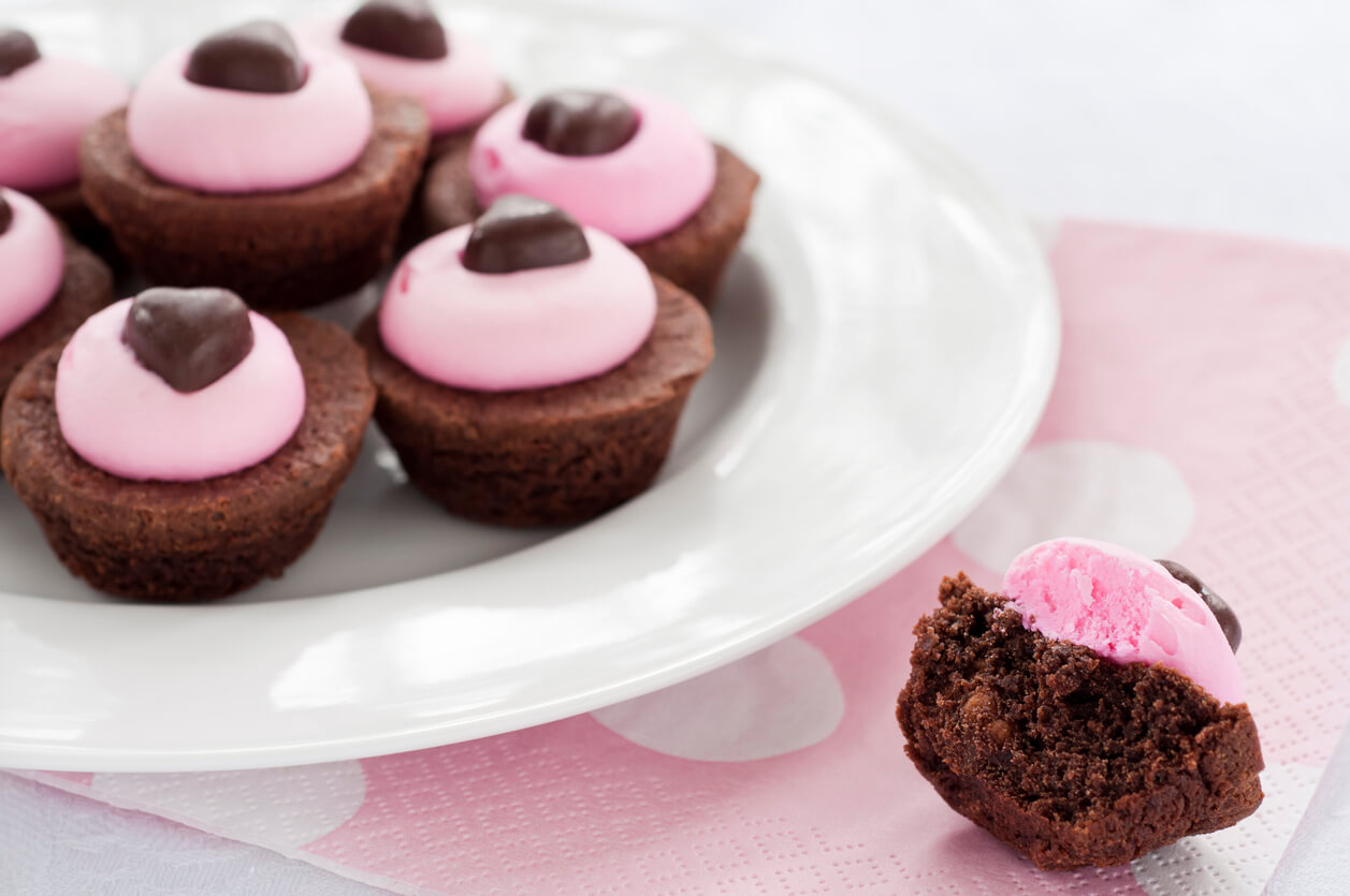 Plate full of brownies decorated for Valentine's Day with one half brownie on the side.