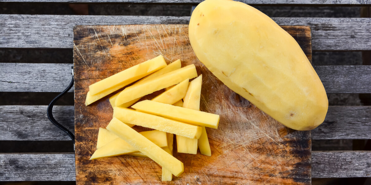 Cut potatoes, french fries, on a cutting board.