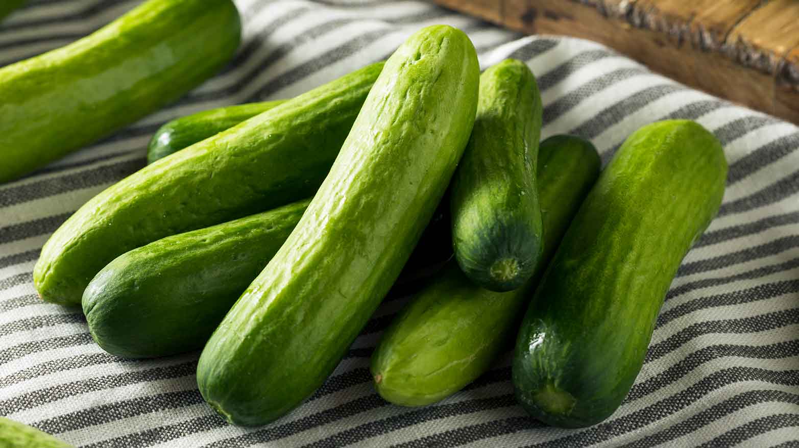 Several cucumbers laid out on a dish towel