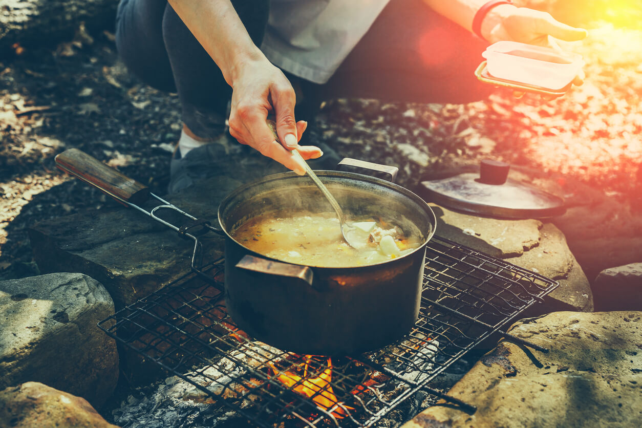 Unrecognizable woman tourist cooking on campfire in forest. Concept Tourism Camping Survival Wildlife