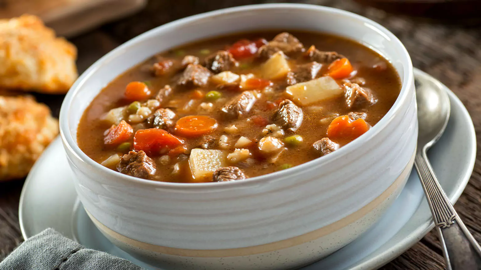 A large bowl of beef and barley soup with carrots.
