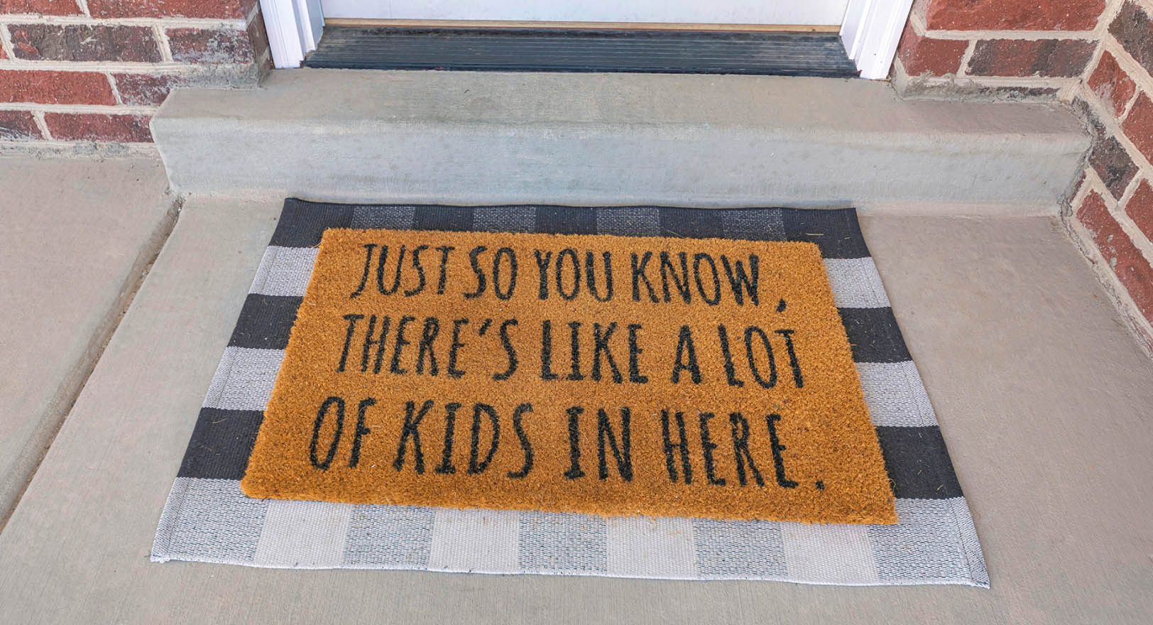 A photo of a humorous welcome mat that reads “Just so you know, there’s like a lot of kids in here."