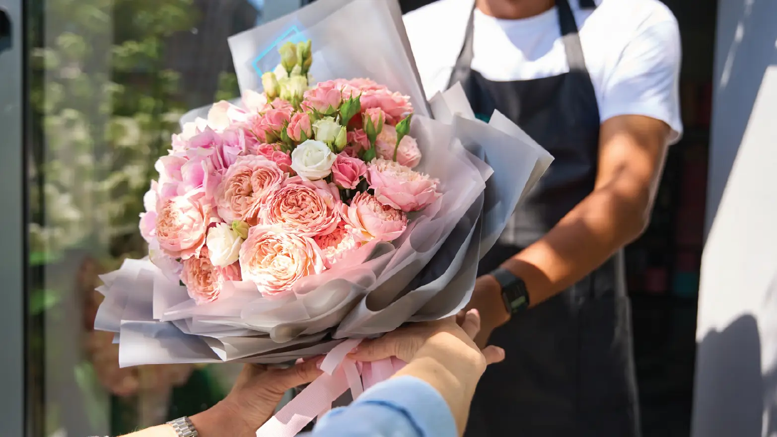Hands accepting a delivery of a fresh sympathy flower bouquet at a home front door as a condolence gift.
