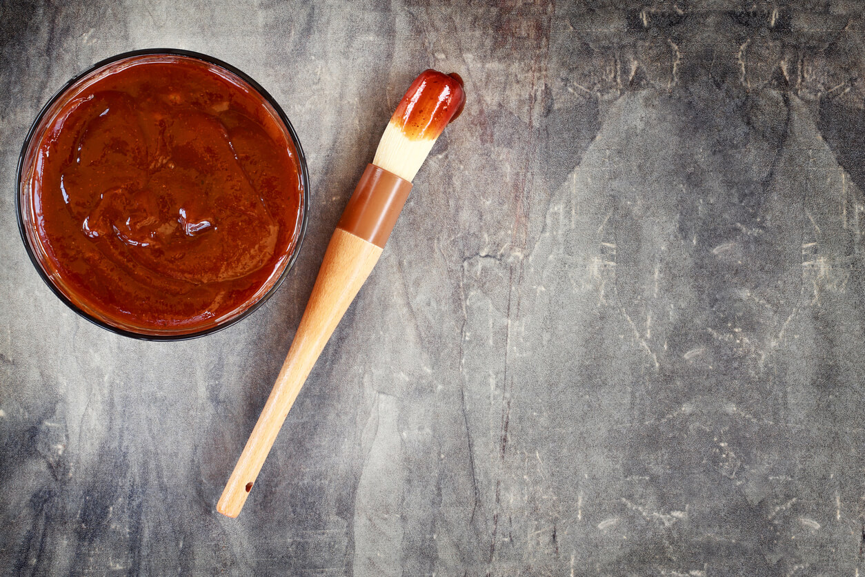 Barbecue sauce with basting brush over stone table.