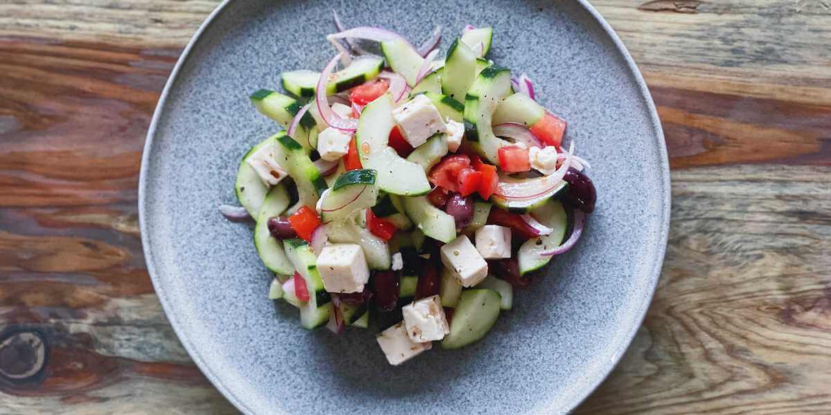 Greek Salad on a plate on top of a wood table.