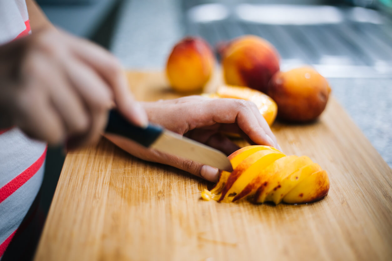 Close up of woman slicing peach.