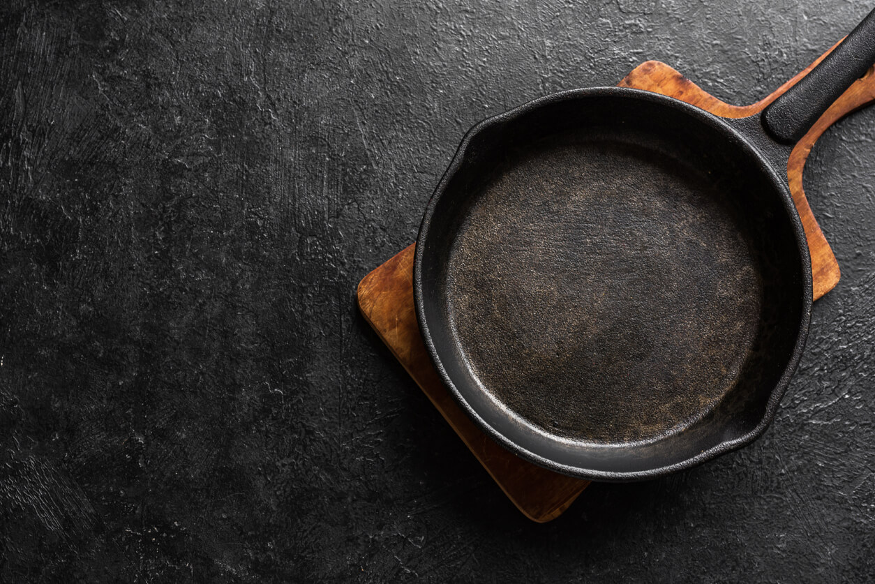 Empty cast iron frying pan for cooking on black background.