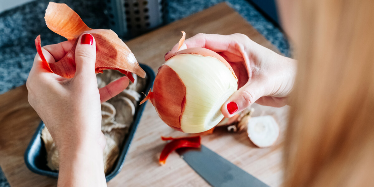 Peeling an onion on a cutting board.
