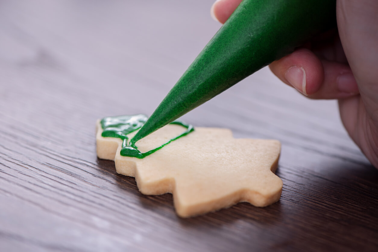 Close up of drawing Christmas tree sugar cookie on wooden table.