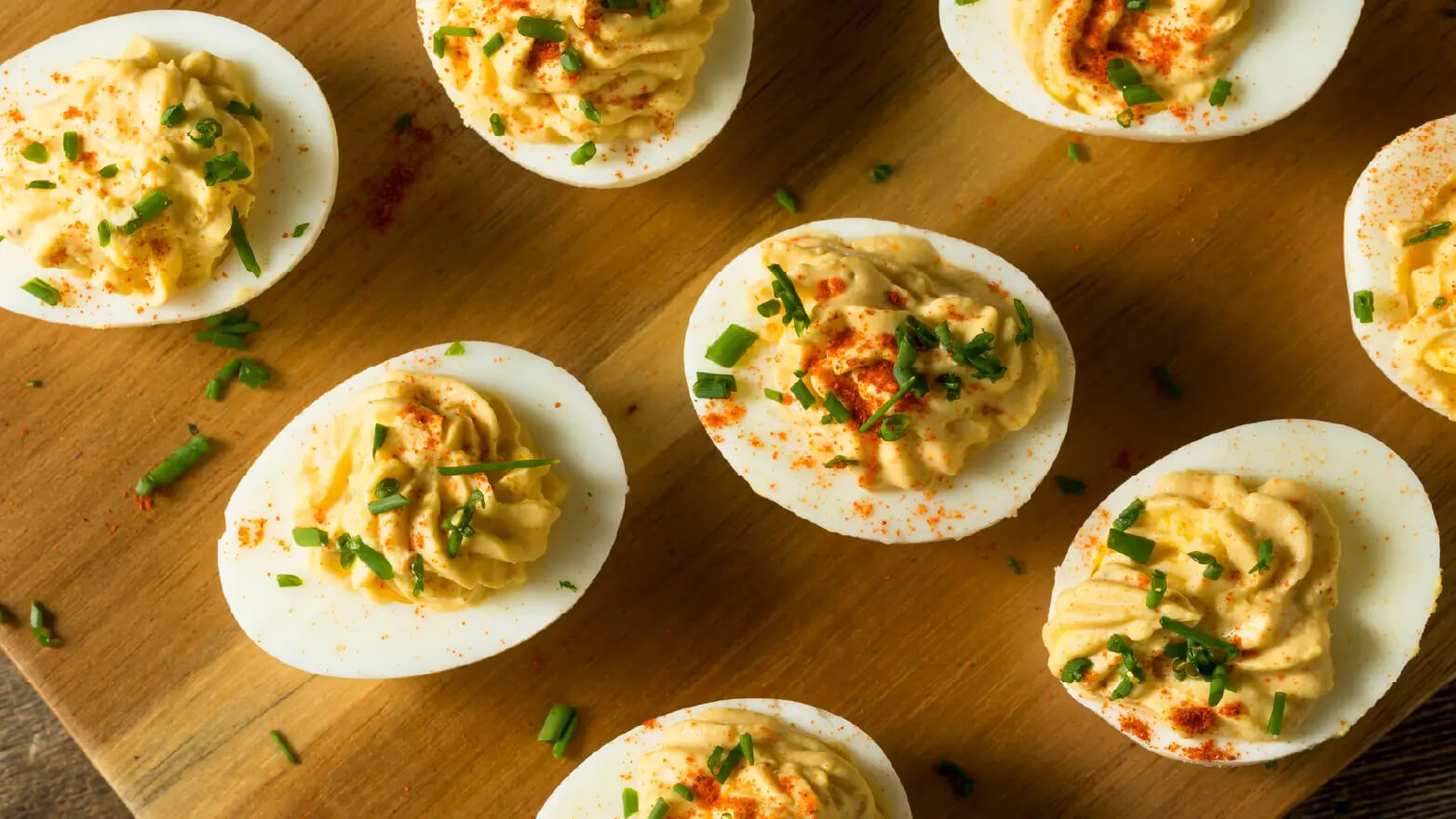 Stock image of deviled eggs topped with green onion and paprika
