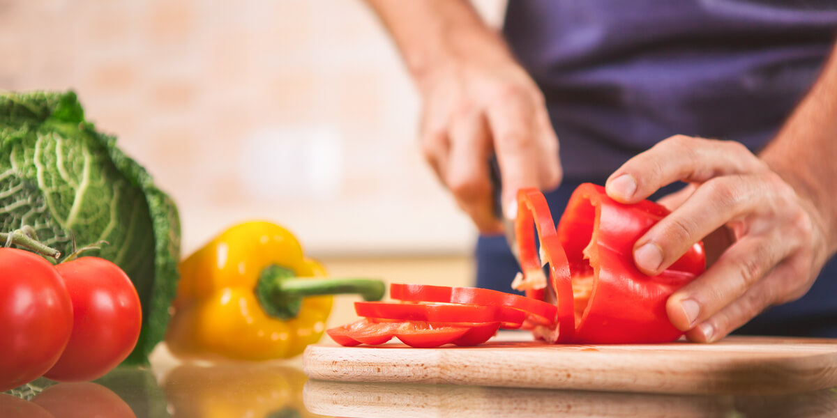 Chopping a red bell pepper into rings on a wooden cutting board