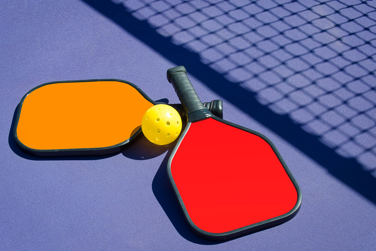 Pickleball - Two Paddles and A Ball in Net Shadow