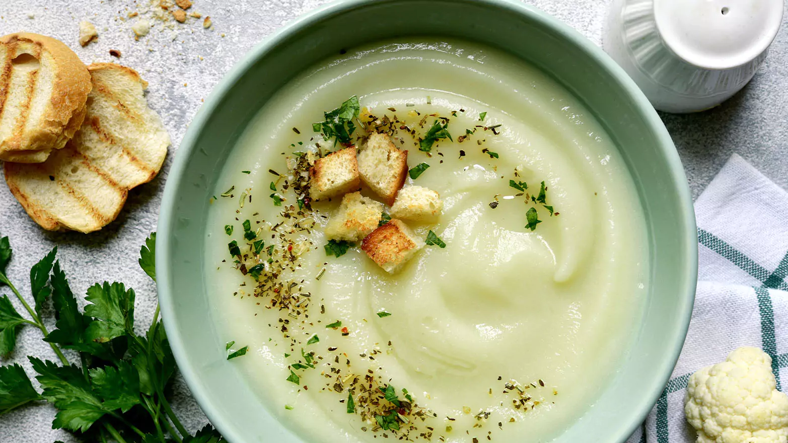 A bowl of creamy celery soup with garlic croutons.