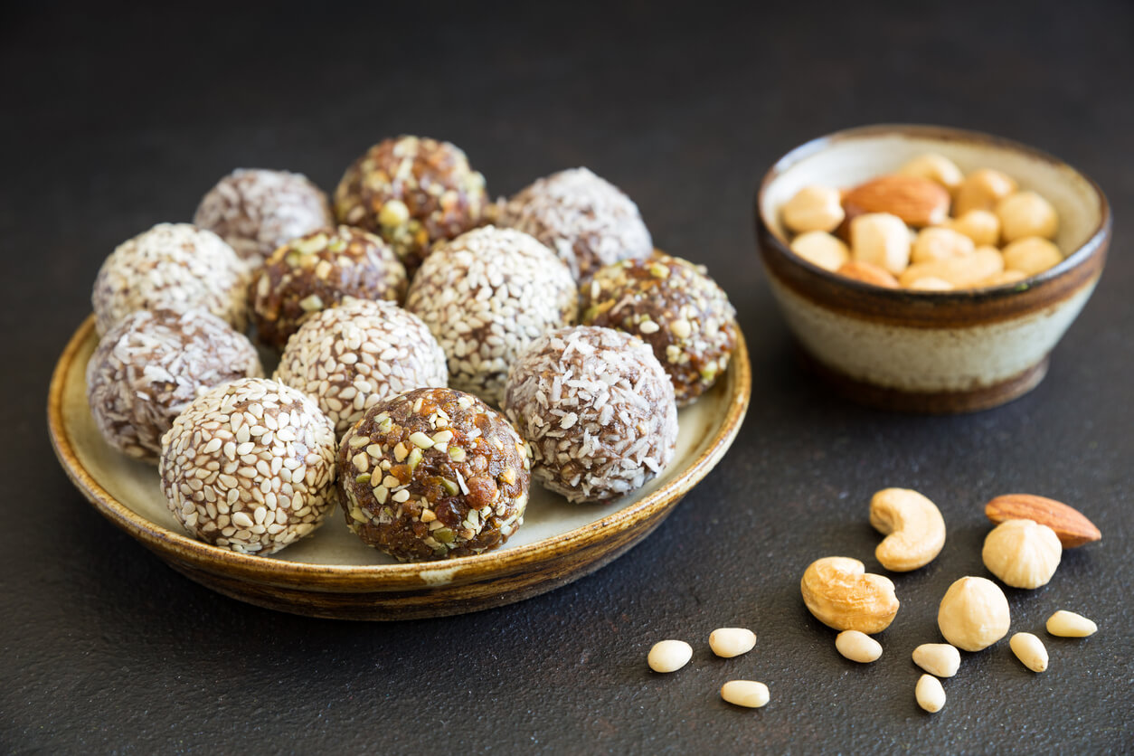 Homemade raw candy energy balls with almond, cashews, peanut butter and hazelnuts on the plate on the dark background close up. Organic snack. Vegetarian food.