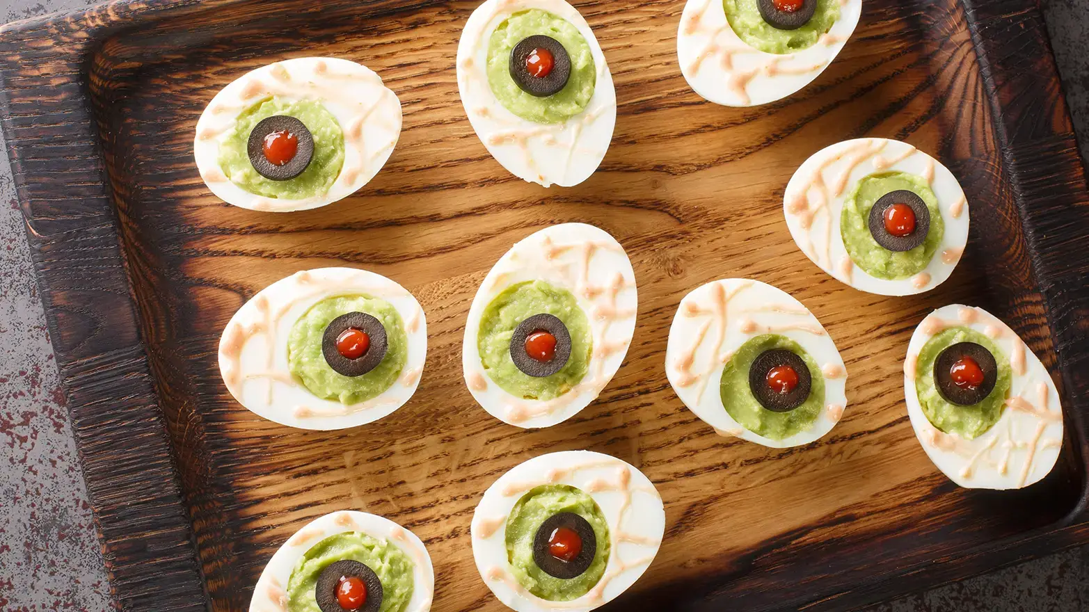 deviled eggs with green filling and stuffed olive eyes.
