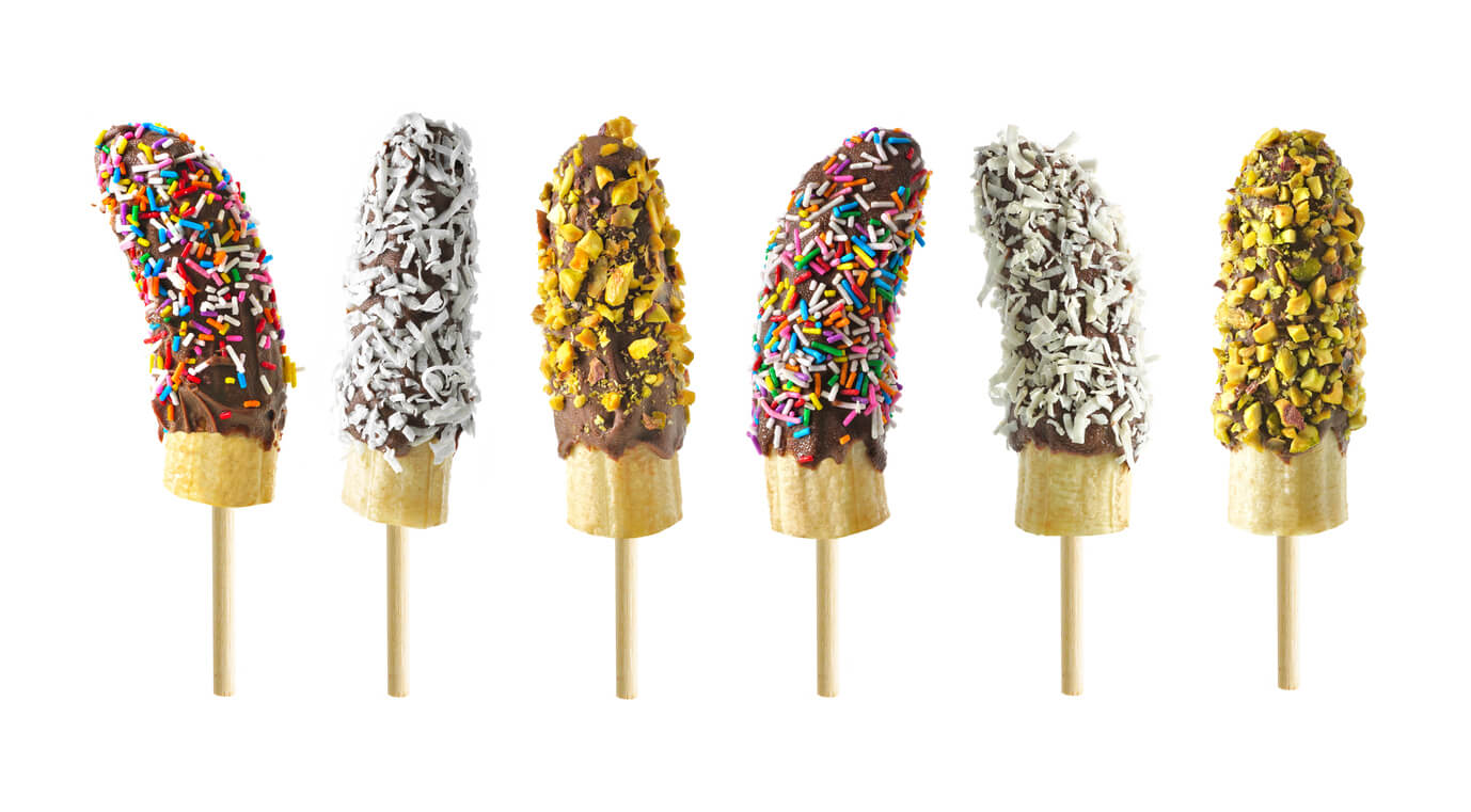 Frozen chocolate dipped banana pops with an assortment of sprinkles, nuts and coconut.