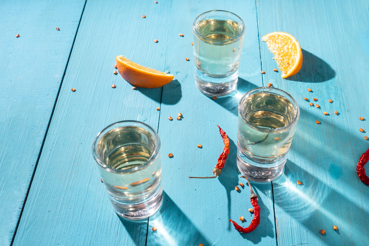 Mezcal shots with slice of orange fruit