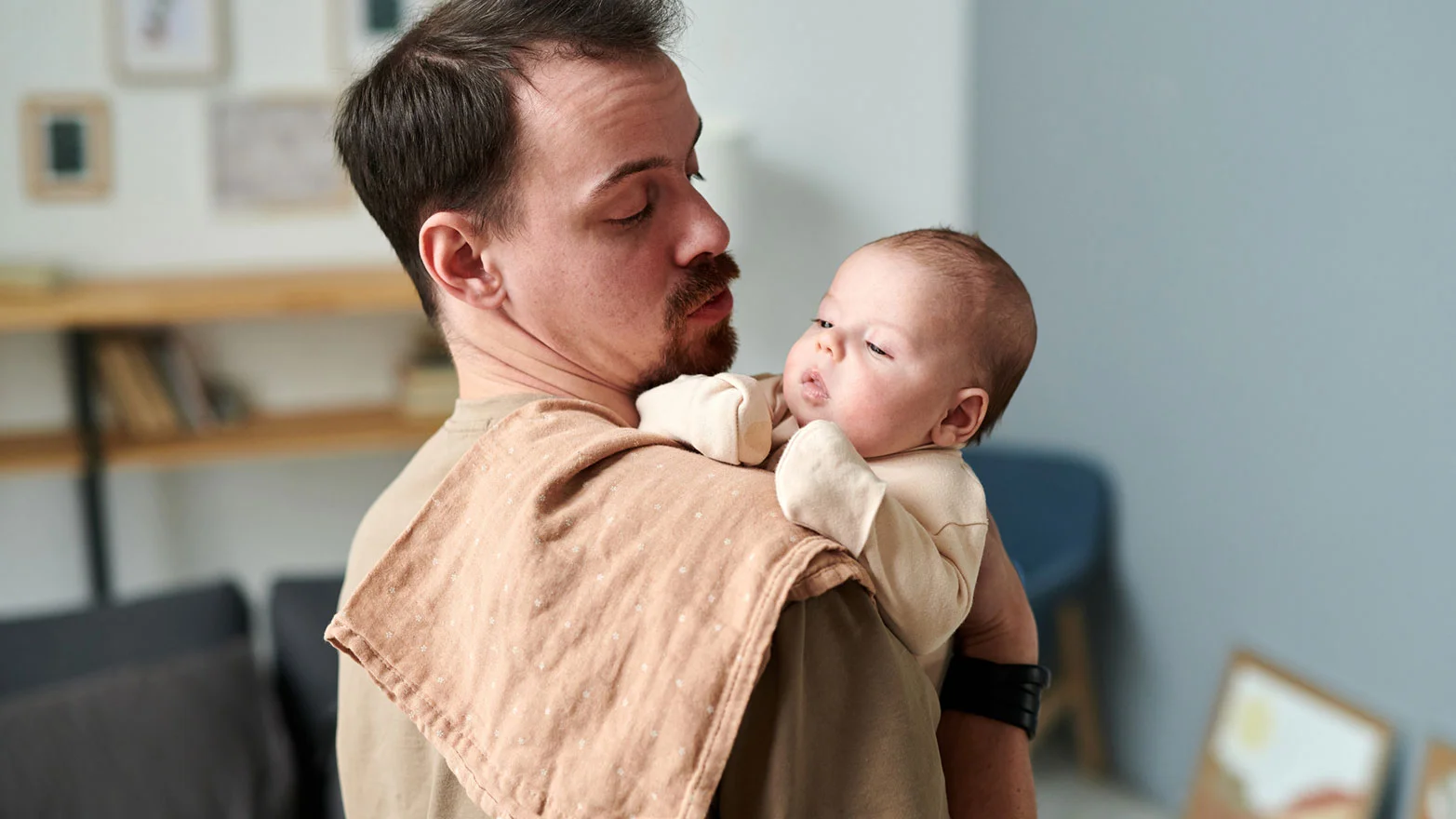 A stock photo of a man holding a baby, with a burp cloth draped over his shoulder.