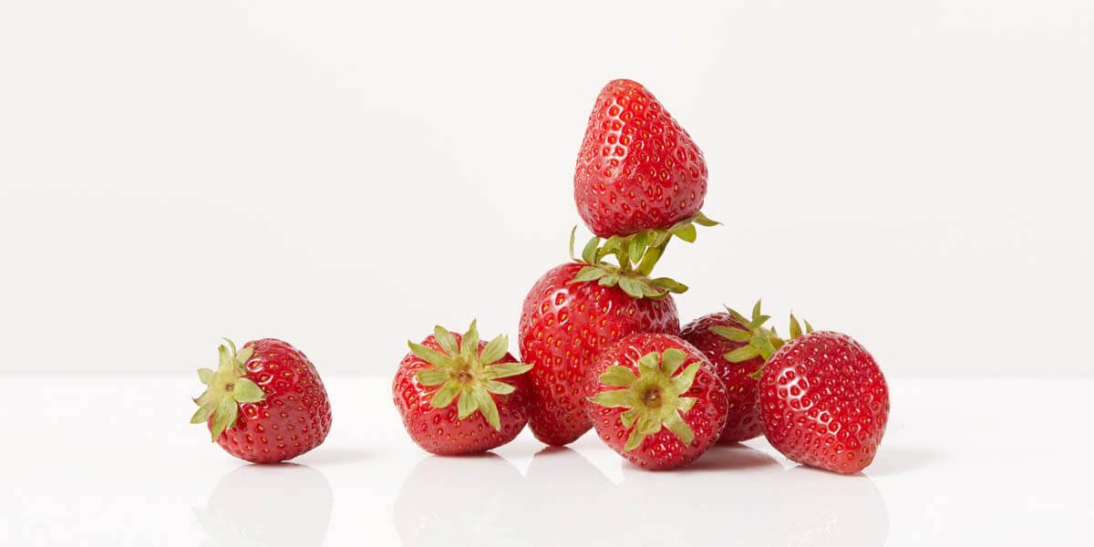 Strawberries, grocery store produce, on a blank background.