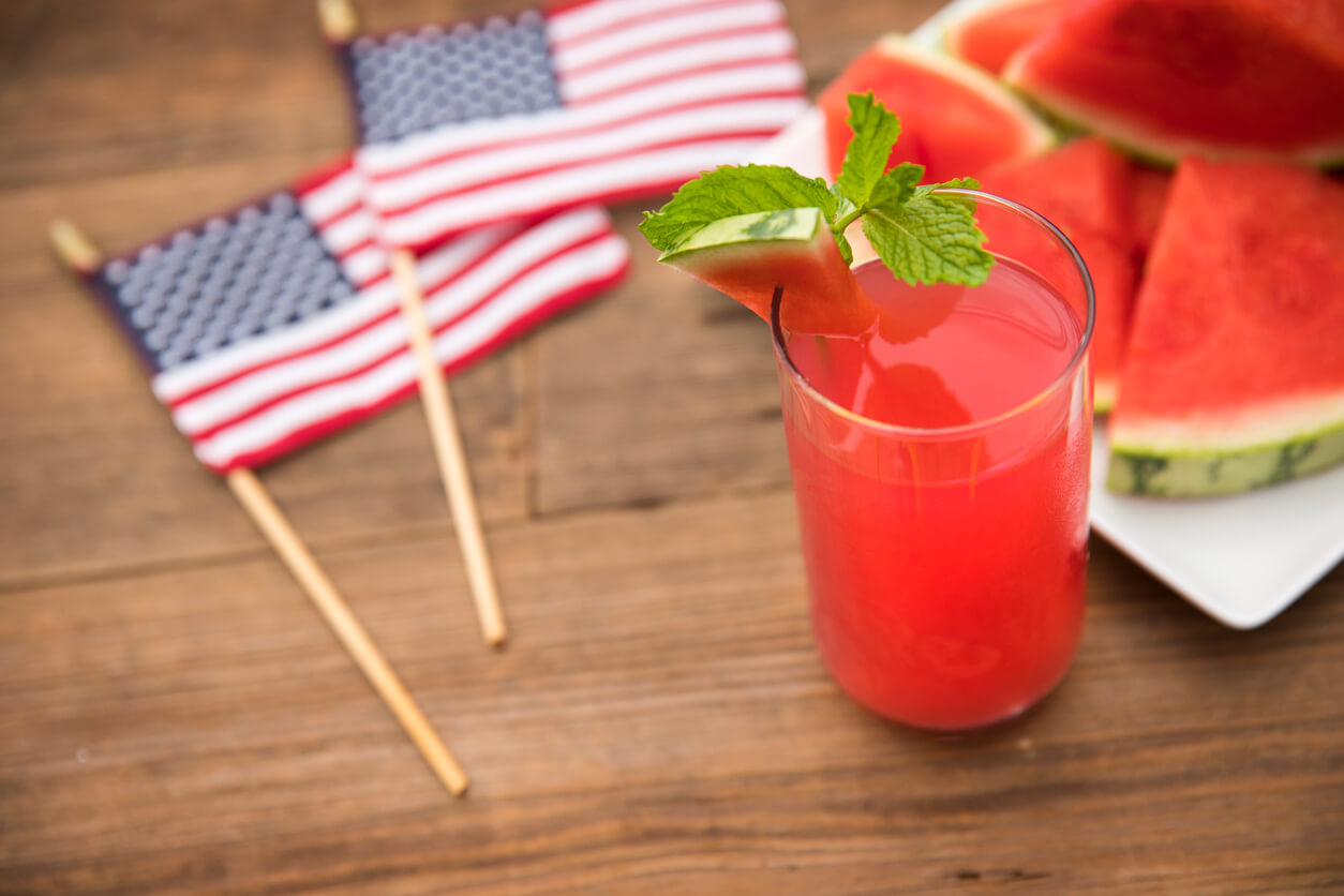 Fresh glass of watermelon juice and mint leaf with slices of watermelon in the background