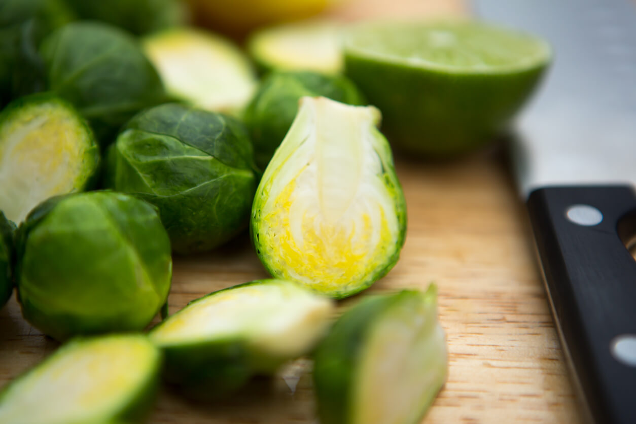 Cutting brussels sprouts on a cutting board.