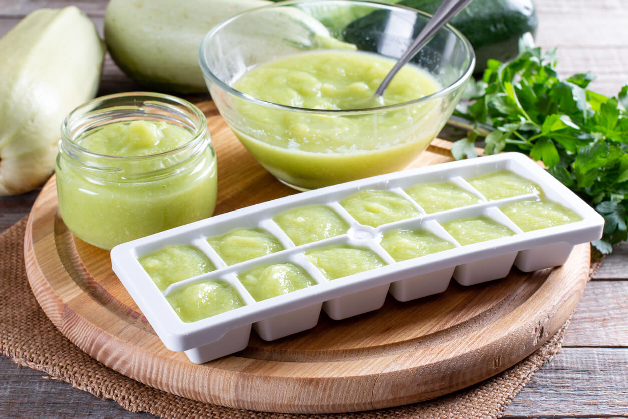 Zucchini puree in ice cube trays ready for freezing on a cutting board on a table.
