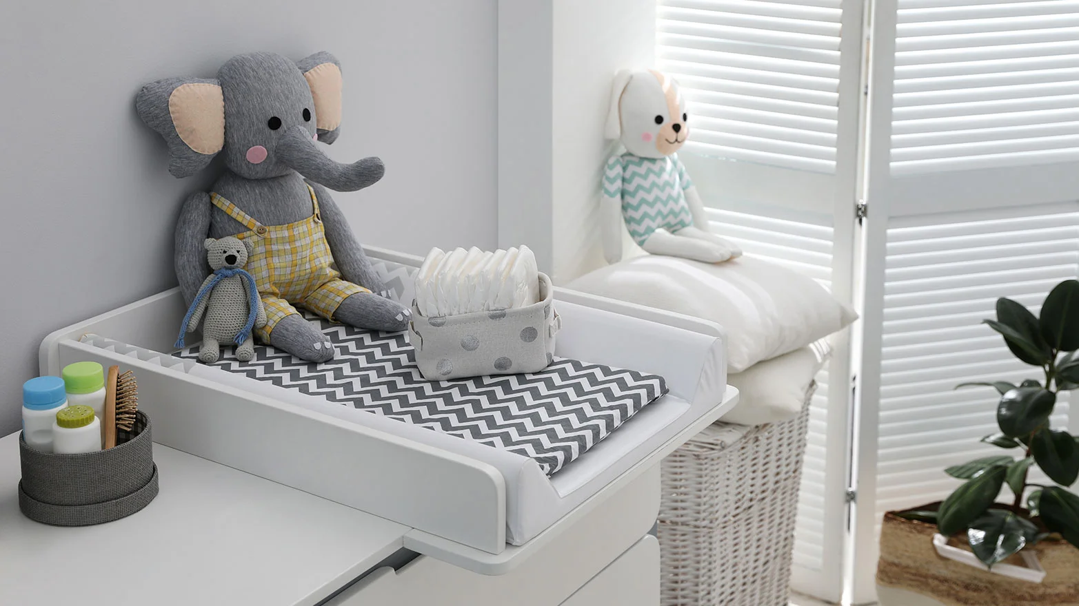 A stock photo of a diaper changing pad in a nursery with grey decor and toys.