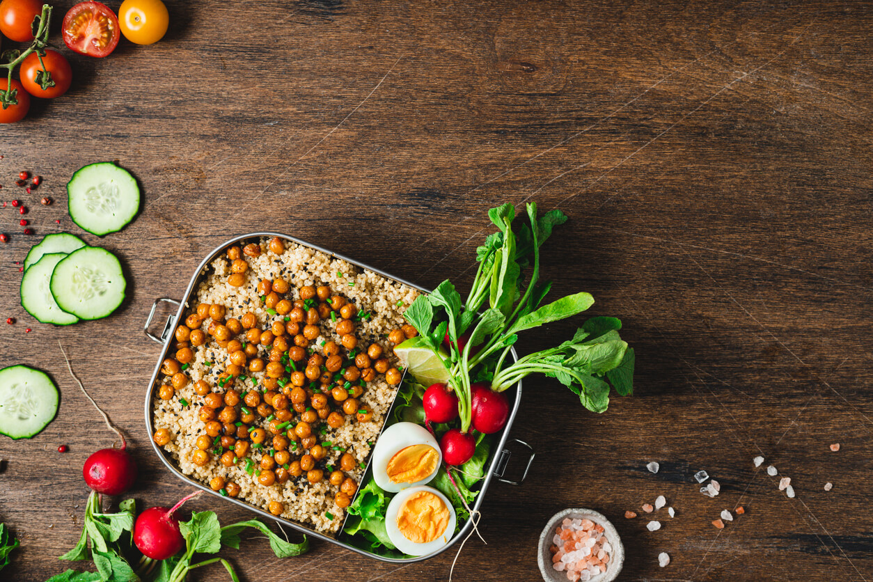Top view of lunch box with healthy food on wooden table.