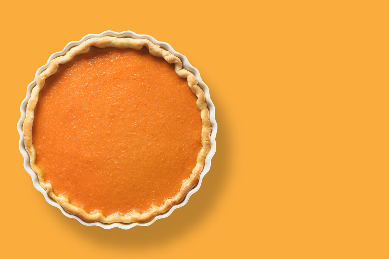 Homemade tasty pumpkin pie with autumn decorations and leaves for Thanksgiving Day on white.