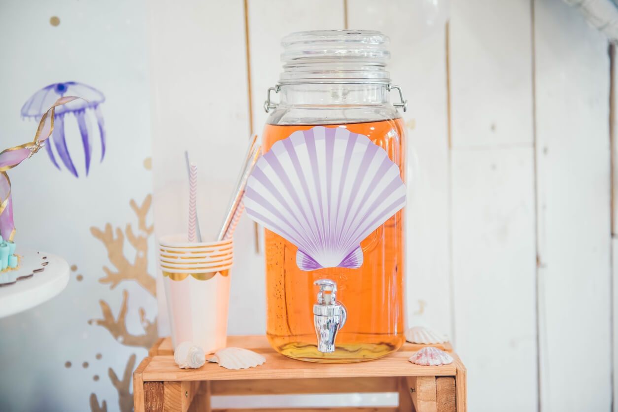Lemonade in glass jar with tap on wooden stand indoor. Mermaid Candy Bar.