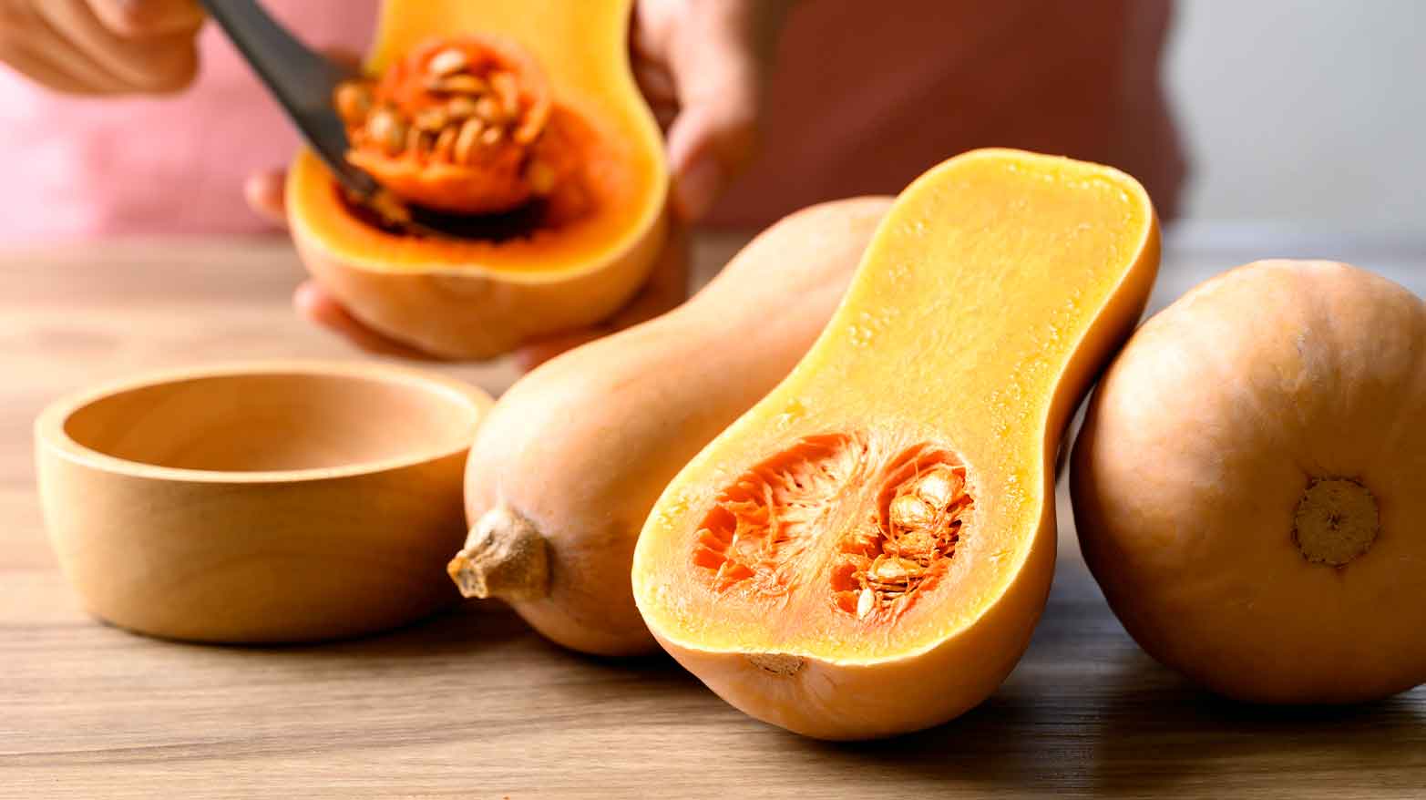 Someone scooping out the seeds of a butternut squash