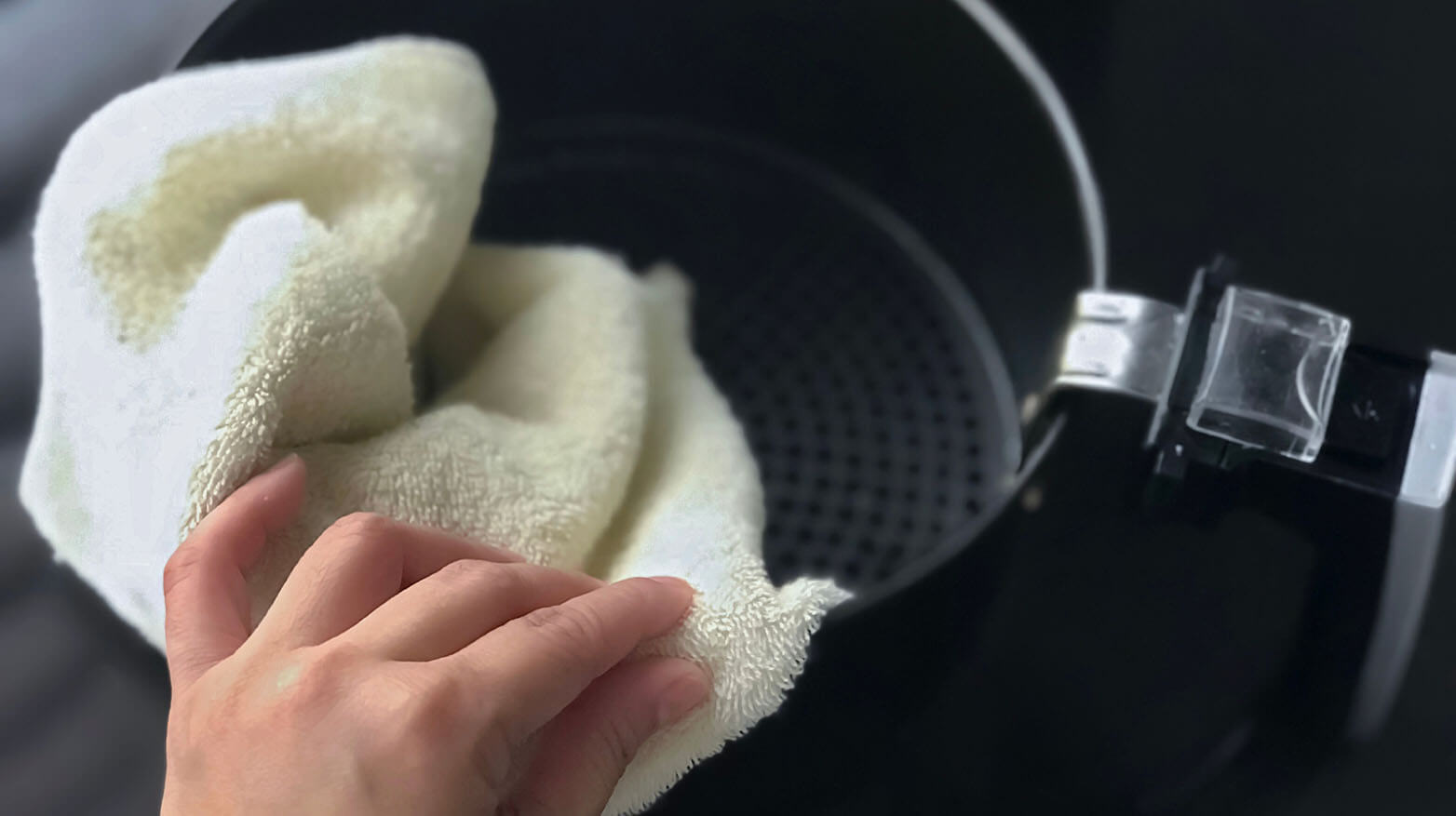 Someone wiping down the inside of an air fryer.