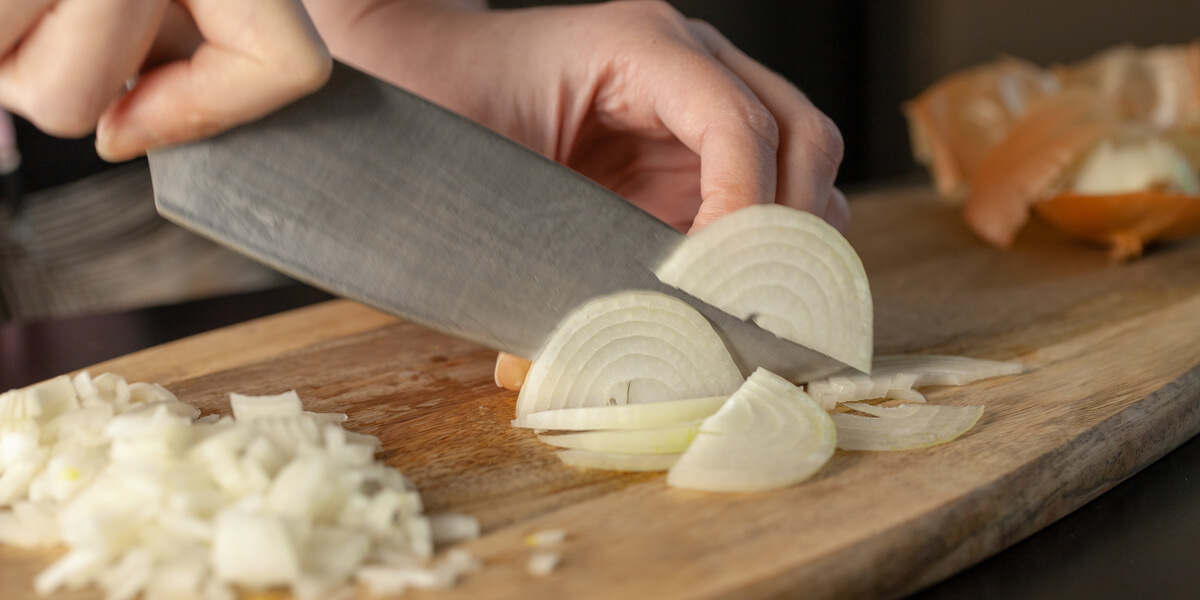 Cutting an onion on a cutting board.