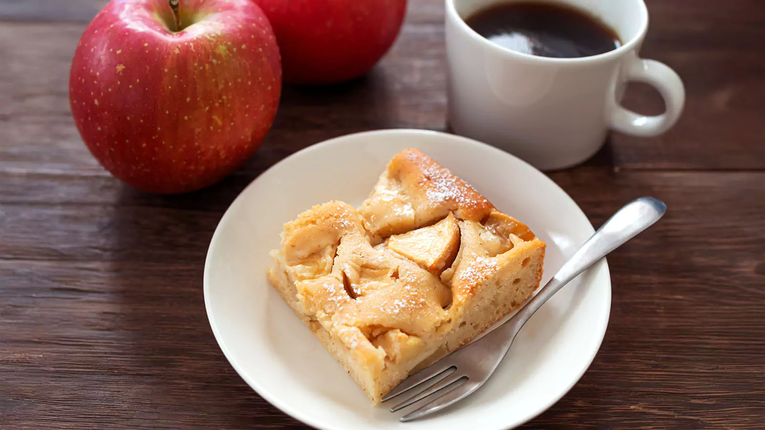 a serving of apple cinnamon French toast casserole next to a mug and apples