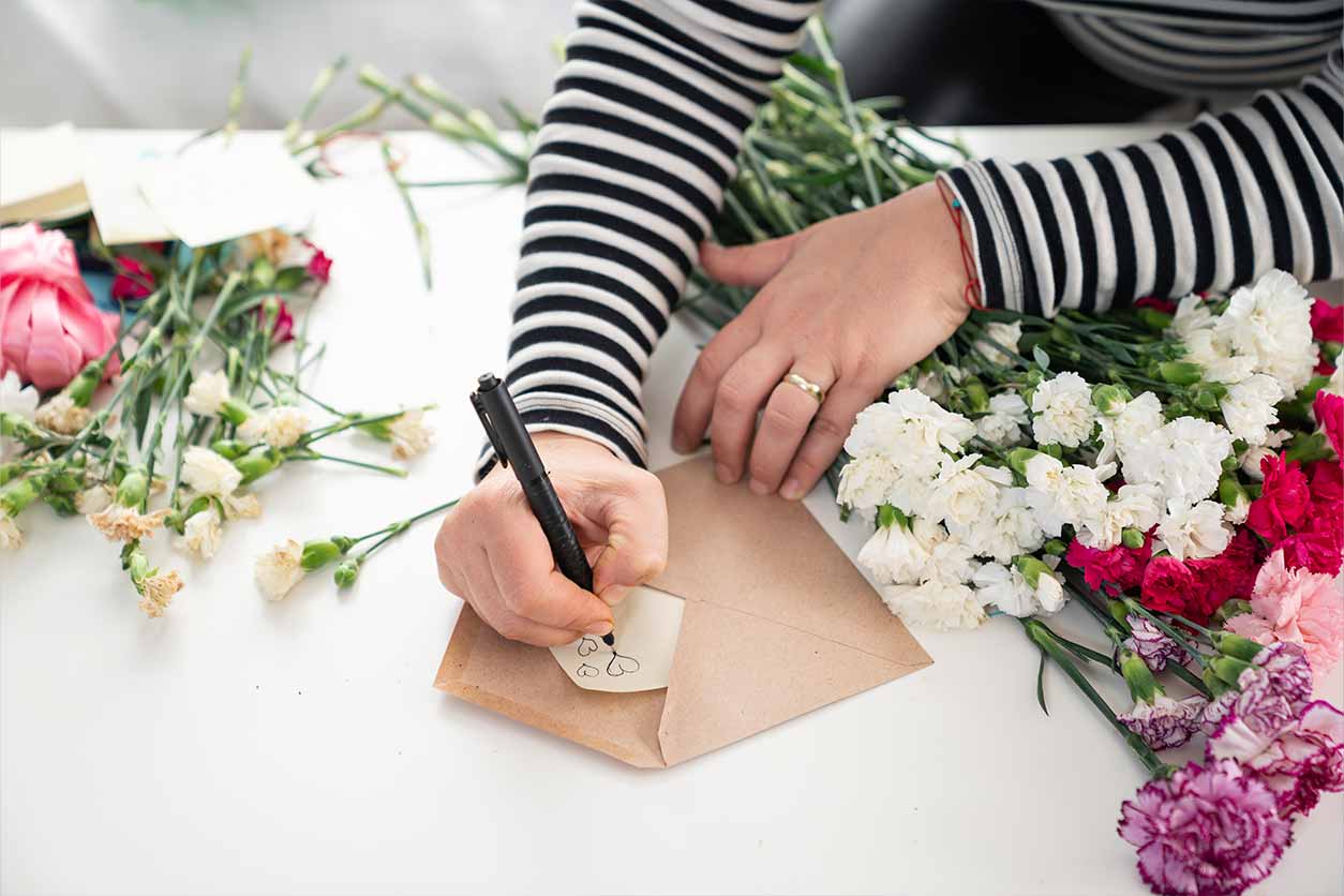 a cropped photo of a woman writing a Valentine’s Day note card