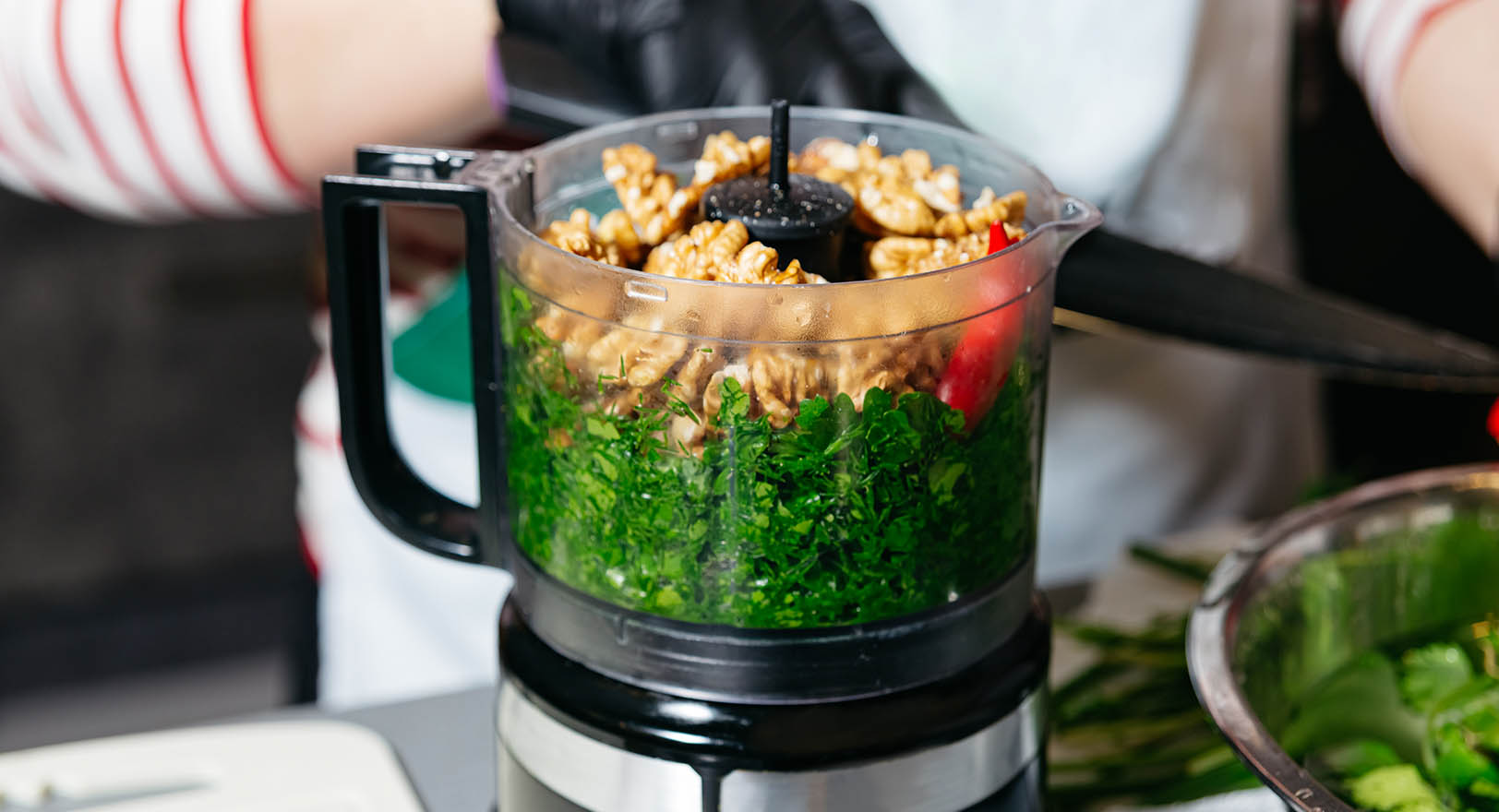 A close-up photo of ingredients being inserted into a food processor.