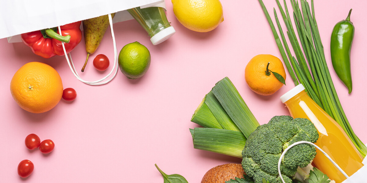 Paper bags full of vegetables and fruits on pink background. Top view, shopping and delivery concept