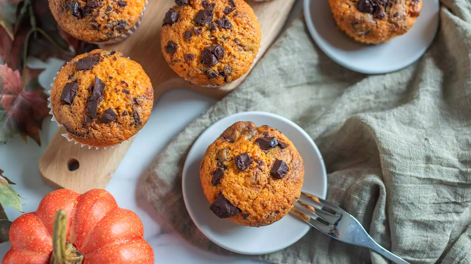 top-down view of chocolate chip pumpkin muffins on a tablecloth