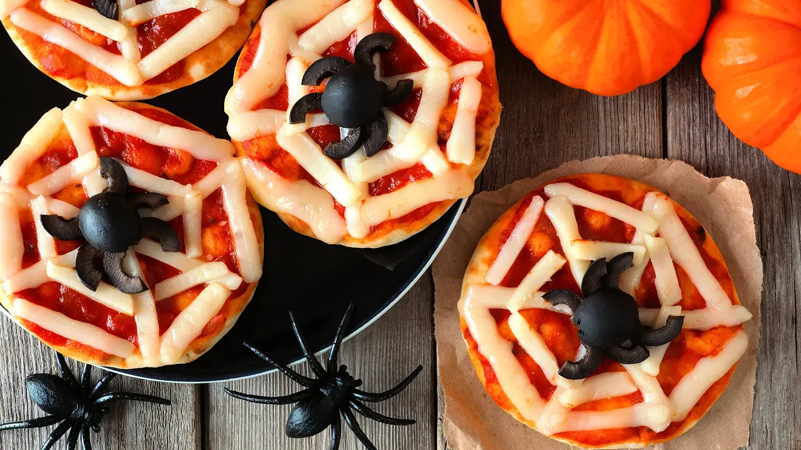 Mini pizzas with cheese spider webs and olive spiders