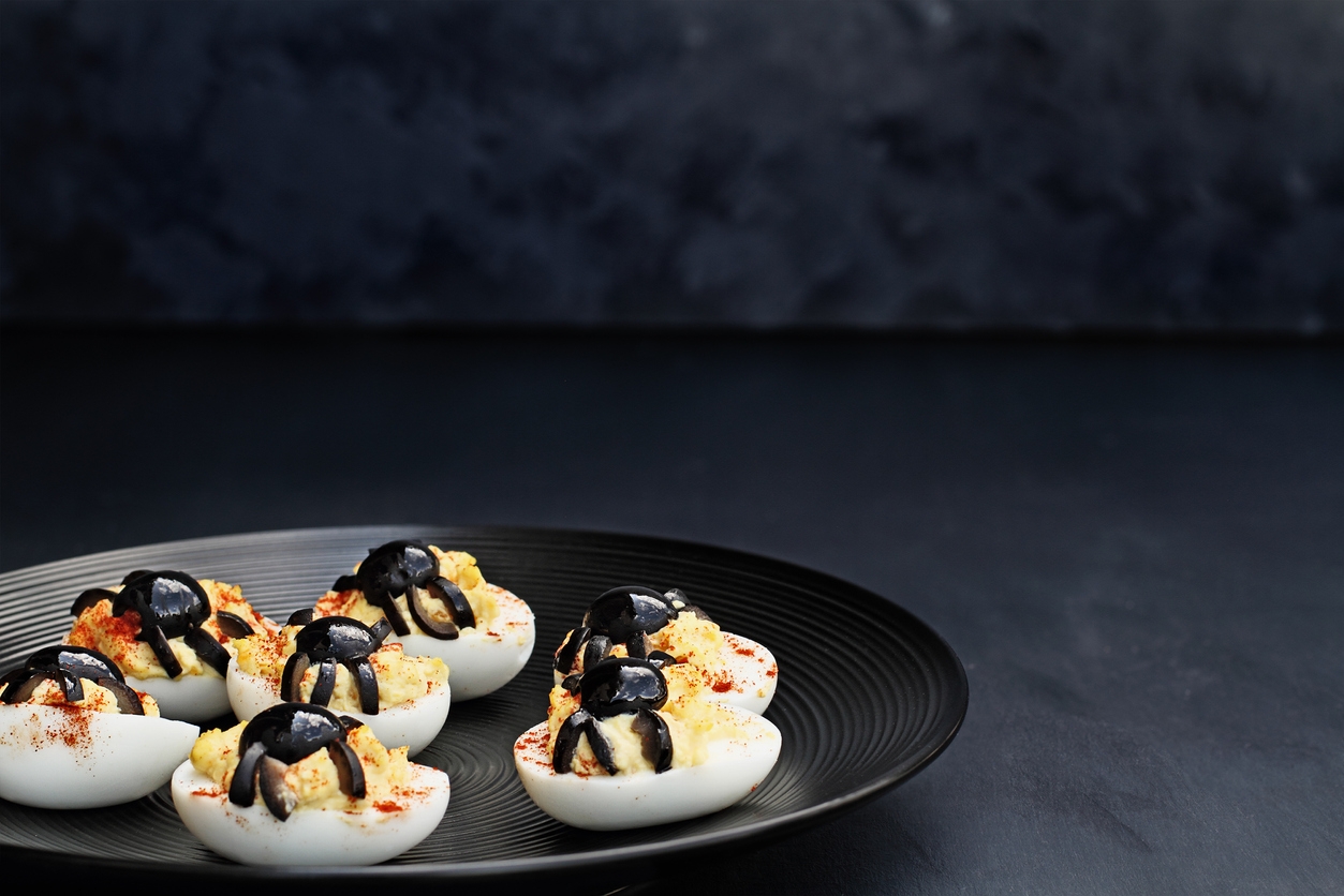Fun food for kids. Halloween boiled eggs with black olive spiders on top of them. Alternative to candy. Free space for text.