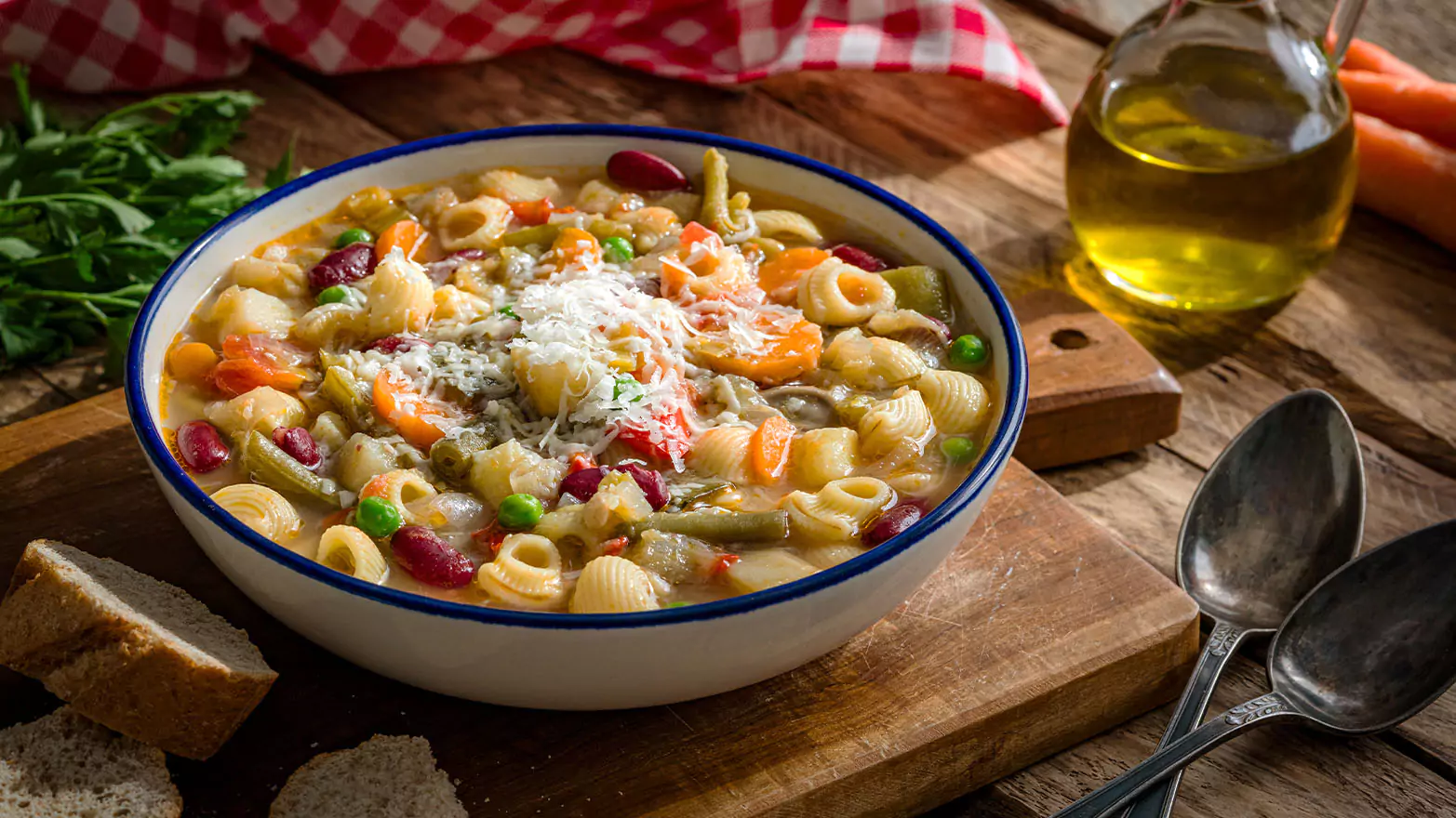 A bowl of Italian minestrone soup on a wooden serving board.